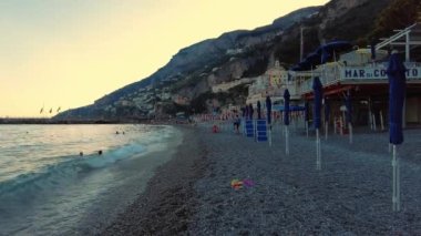 Denizde top oynayan iki çocuk, okyanus. Kumsalda birlikte top oynayan iki oyuncu çocuk. Gün batımı renkleri. İtalya 'da, Napoli kıyısında, Amalfi kıyısında oynayan çocuklar. Dağlı günbatımı arkaplanı