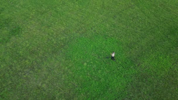 空中からの眺めは金属探知機の男の上を飛んでる 畑の中を一人で歩く 金属探知の若者だ 宝探し金掘り 4K空撮 — ストック動画