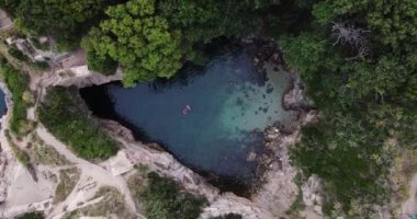 İnsanlar gizli bir plajda yüzüyorlar. Bagni di Regina Giovanna, Sorrento, İtalya. Mavi göl mağarası plajı turistler için, yazın mavi suyla. Mağara kayalıkları plajı. Yüksek kaliteli FullHD görüntüler. 