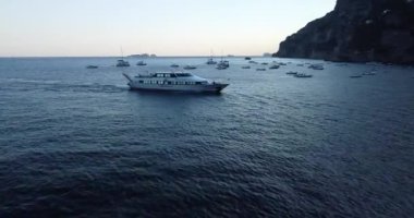 Mavi turkuaz Akdeniz 'de yüzen tekneler. Lüks yatlar ve arka planda dağlar. İnsanlar teknelerde dinleniyor, günlerinin tadını çıkarıyor ve yüzeyde yüzüyorlar. Mavi su. 
