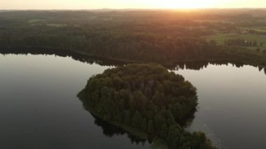 Gün batımlı bir göldeki adaların havadan görünüşü. Yeşil pofuduk adalar ve yeşil orman hava aracı güneşli bir yaz akşamında gün batımına bakıyor. Şafakta sakin bir su, güneşli bir sabah. Estonya doğası.