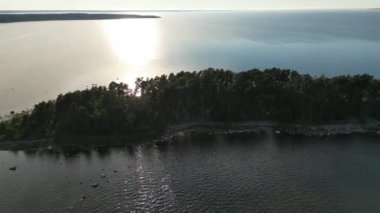Aerial tropical golden sunset over ocean water. Sand beach and crystal clear ocean water. Sun setting reflection on seascape, sea under a moody sky at sunset. Calm waterscape at sunny evening.