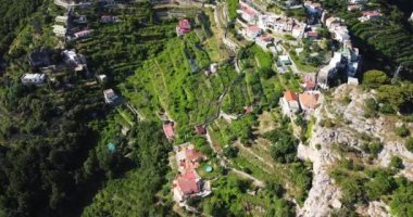 Aerial top down drone shot above the winding mountain roads and houses. Beach life landscape. High mountain village. White resort houses in top of the mountain. Holiday and travel. Travel journey 