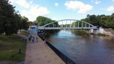 Timelapse of People walking by promenade next to river. Riverside bay view bridge panorama, a stone bridge over a river. People time lapse hyper lapse walking over bridge. Summer view. 