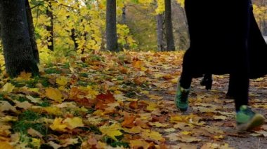 Woman running with Slim female legs and feet close up on autumn morning. Two women walking past. Young fitness sport woman running on autumn road. Slow motion of Young women exercising healthy concept