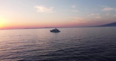 Turquoise blue water sea with yacht sail with sunset. Aerial top down view of a boat on a mediterranean sea. One ship boat in beautiful nature ocean landscape. Motor boat moving over the deep blue sea
