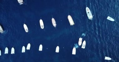 Aerial top-down view of docked sailboats. Aerial view of a wealthy billionaire luxury super yacht on blue ocean. Famous turquoise clear water beach Italy, Positano. Docked in the harbor on a sunny day