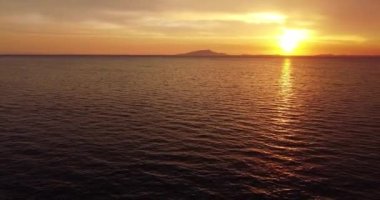 Dramatic sea sunrise. Drone aerial view dolly side panning over paradise beach sunrise. Burning sky and shining golden waves. Ocean beach sunrise and dramatic colorful sky clouds. Cloudscape over sea