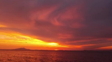 Majestic sunset or sunrise landscape. Beautiful cloudscape over the sea. Amazing light, pink and red sunset. Boats moving past. Red purple orange blue pink sunset sky cloud. Red sky, yellow sun.
