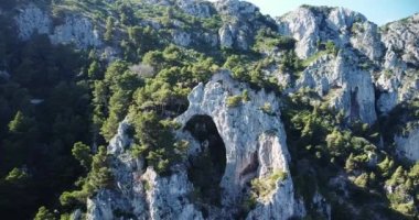 Aerial shot epic mountain ridge. Stone Arch Catedral, Rock Formations. Natural rock formation, Capri Island, Napoli, Italy. A natural landmark. Jagged limestone rock formations, aerial drone footage.