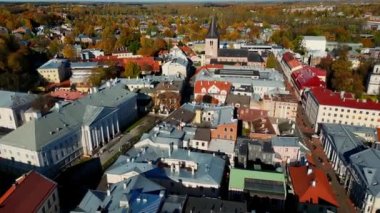 Aerial view of autumn trees in city and roofs of buildings. Colorful autumn trees during sunset, View of Tartu University, Estonia. Forest leaves changing color in Autumn. Tartu town hall.