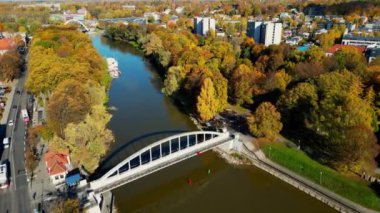 Cinematic Ariel Autumn footage. Cinematic aerial flying over river with view downtown. Beautiful autumnal scenery in the city. Tartu, Estonia. Golden hour sunset, panorama in Autumn with skyscrapers.