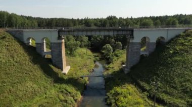 Aerial view of a train track bridge, railway bridge over the River Rauna, Latvia. Highest railway structure in Baltic countries. Endless railway without train. Empty straight single-way track. 