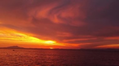 Majestic sunset or sunrise landscape. Beautiful cloudscape over the sea. Amazing light, pink and red sunset. Boats moving past. Red purple orange blue pink sunset sky cloud. Red sky, yellow sun.