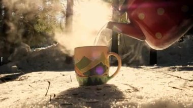 Pouring Tea Into Cup. Hot drink on the background of wild nature. Steaming hot water tea. Traveler Enjoying Hot Tea In Mountain Mug. Hot steamy tea pouring. Cold winter day in forest.