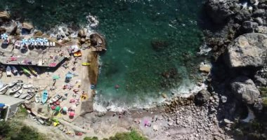Tropical beach aerial drone top down view sea blue waves break on rock and sand. Colourful sun umbrellas and people relaxing on a summer day. Beautiful white tropical rocky beach. Italy, Positano.