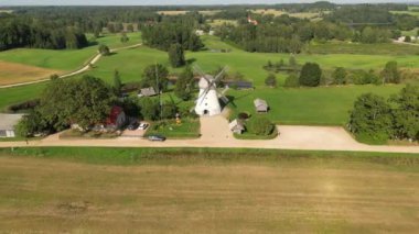 Aerial view of Araisi Windmill in Latvia. Dutch type mill. Antique wooden windmill. An old windmills in the countryside. Alternative energy. Wind turbine moving and rotating. On top of the hill. 