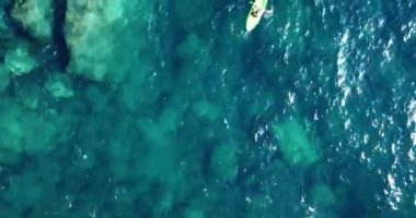 Mavi Şeffaf Su 'da Stand Up Paddle Board silueti. Denizde kürek çekerek ayağa kalk. - Süper. Ekstrem Yaz Su Sporları. Sağlıklı yaşam tarzı. Sörf. Turkuaz suda kürek çeken kürek tahtası. 