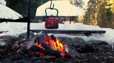Scenic bright flame burning in slow motion. Slow motion close up of outdoor fire place in the forest with a teapot. Making tea on a fireplace. Cozy atmosphere. Winter scenic mountains covered snow.