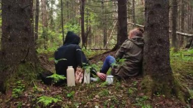 Ormanda oturup çay içen iki uzlaşılmaz insan. Doğanın tadını çıkarıyorum. Çam ormanlarında oturan sakin insanlar ve meditasyon, rahatlama ve sağlıklı yaşam konsepti. Sıcak çay içiyorum. 