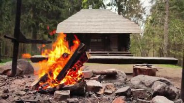 A cozy evening by the fireplace and log house on the background. Old abandoned rural wooden house with fireplace. Flames over wooden logs. Wooden log in fire place cozy atmosphere. High quality 