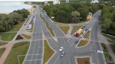 Arabalar deniz kıyısının yanındaki yolda ilerliyor. Deniz kenarındaki otoyol. Hava görüntüleri, insansız hava aracı trafik yolunda uçuyor. Estonya. Yeşil şehir ekonomisi. Araba trafiği. Trafik karayolu taşımacılığı.