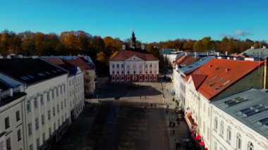 Aerial view of autumn trees in city and roofs of buildings. Colorful autumn trees during sunset, View of Tartu University, Estonia. Forest leaves changing color in Autumn. Tartu University hall. 