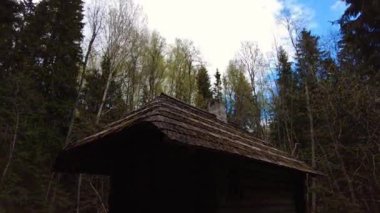 Timelapse of a wooden cabin in the woods, clouds moving past fast. Looking up with the camera. Spring feeling. Wooden cabin in the woods. Cozy bedroom with fireplace. Hyperlapse. Cloudscape. 