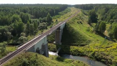 Aerial view of a train track bridge, railway bridge over the River Rauna, Latvia. Highest railway structure in Baltic countries. Endless railway without train. Empty straight single-way track. 4k 