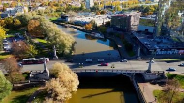 Stunning Aerial shots of bridge over river at sunset with reflection. Cars and people walking over bridge that can seen from reflection. Colorful autumn morning. Trees different colors. Yellow river.