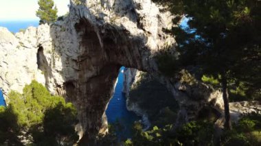 Arco Naturale, limestone arch that forms a bridge between two pillars of rock. Unique rock formation. Travel destination, Capri island, Italy. Blue water. Natural limestone arch. High quality. 