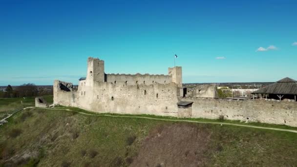 エストニアの風光明媚な田園風景の中に城旗を振って 美しい石と北の歴史的遺跡の美しさ 草の丘と崖の塔に腰掛けて石城を課す — ストック動画