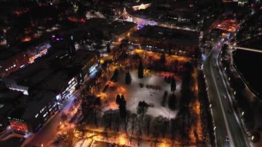 Kış zamanı kar yağışı eşliğinde geceleri gökyüzü manzarası. Kışın gece çekilirdi. Gece sokağı. Arka planda Noel pazarı var. Canlı güzel renkler. gece drone video kuşları görüntüsü.