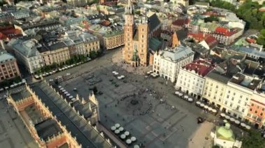 Yukarıdan Market Meydanı, Krakow 'daki eski şehir merkezi manzarası. Belediye binası olan Rynek Glowny. St. Marys kilisesi ve güneşli bir akşamda yürüyen insanlar. Polonya, Krakow 'daki ünlü katedral.