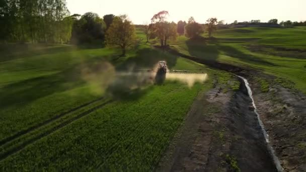 日落时分 作物喷雾器在大豆田上喷洒农药的空中景观 旁边有一架拖拉机向麦田喷洒抗病药物 空中射击紧随其后 农用拖拉机使用的化学品 — 图库视频影像