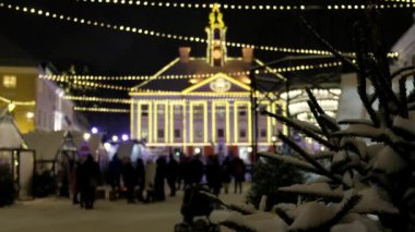 Noel Birası ve Sıcak Şarap, Tartu 'daki Estonya Noel Pazarı' nda indirimde. İnsanlar Noel ve yeni yıl tatilleri için dekore edilmiş büyük bir mağazanın yanında yürüyorlar. Düşen kar taneleri. 