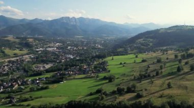 Hava manzaralı resimli dağ köyü. Polonya 'daki Tatra Dağları' nın altındaki Zakopane kasabasının hava manzarası. Zakopane tatil köyü ve yüksek Tatra dağları. Yeşil çam ormanı, tepelerdeki yazlık oteller.