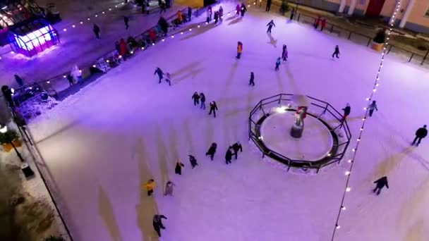 冬の日に大きなオープンエアアイスリンクでスケートする人々のトップビュー 冬のスポーツ活動 スケートの背景 エストニア タンザニアのロマンチックな冬の雪の夜 アーバンアイススケートトップビュー アイス リンク — ストック動画