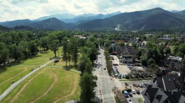 Hava manzaralı resimli dağ köyü. Polonya 'daki Tatra Dağları' nın altındaki Zakopane kasabasının hava manzarası. Zakopane tatil köyü ve yüksek Tatra dağları. Yeşil çam ormanı, tepelerdeki yazlık oteller.