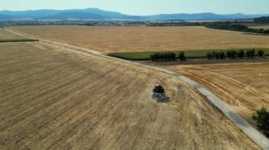 Harrow sistemli bir traktörün üzerinde uçmak ekilmiş tarlalarda tarla sürmek. Tarım temalı endüstriyel görüntüler. Avrupa ülkesi Slovakya 'da tarım. Arka planda Mavi Dağlar.