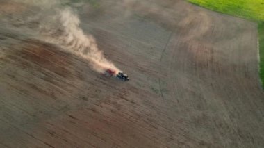 Buğday tarlasında çalışan hasat makineleri. Mısır hasat mevsiminde traktör işi. Tarım makinesini birleştirerek altın olgun buğday tarlası hasat ediyoruz. Tarım traktörü sahaya püskürtücü püskürtüyor.