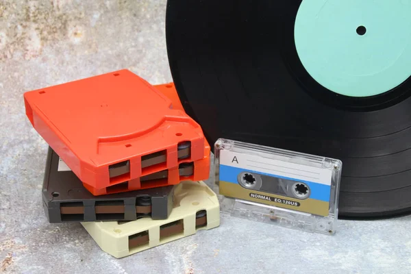 Old audio media, 8 track tape, cassette tape, and vinyl record on old counter