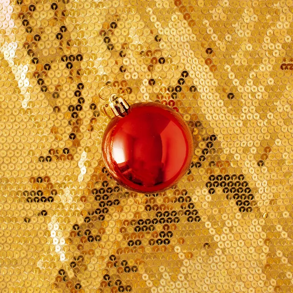 Golden sparkling background with Christmas red bauble. Christmas or New year party concept. Luxury holiday inspiration.