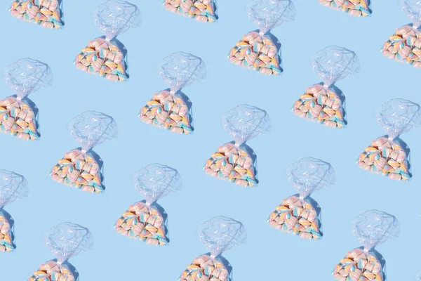Pastel mavi arka planda şeffaf plastik torbaya sarılmış şekerlemelerden oluşan desen. Tatlı yemek konsepti.
