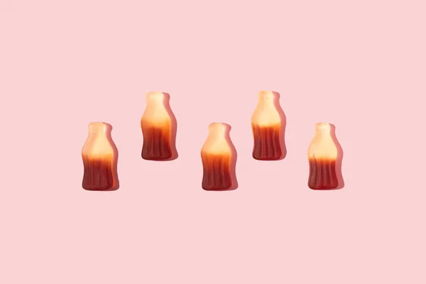 Flaschenförmige Gummibonbons Mit Sonnenlicht Schatten Sortiert Einer Linie Auf Rosa — Stockfoto