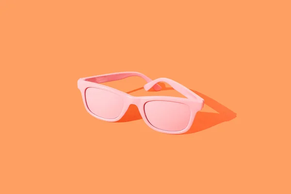 Turuncu arka planda pembe güneş gözlüğü. Yaz plajı partisi fikri. Moda Renkleri.