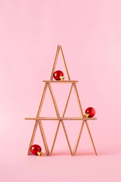 Pastel pembe arka planda süs toplarıyla süslenmiş waffle bisküvilerinden yapılmış Noel ağacı şekli. Noel ağacı konsepti.