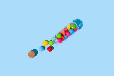 Glass jar with colorful pills on blue background. Concept of medicine, health, pharmacy. clipart