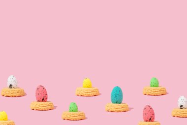 Çerezler ve renkli Paskalya yumurtaları pembe arka planda fotokopi alanı ile. Paskalya kutlamasının soyut fikri