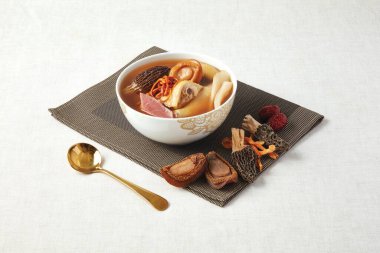 Morel Cordyceps Flower Abalone Haşlanmış Tavuk Çorbası, Hong Kong yemeklerinin peçete tarafından izole edilmiş bir tabakta servis ediliyor.